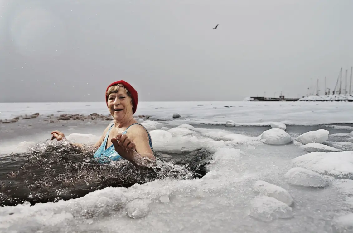 Eine Frau badet in einem Eisloch auf einem zugefrorenen Meer.