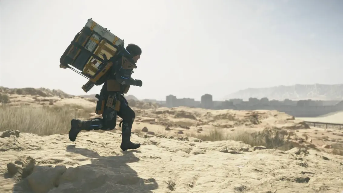 Death Stranding 2 Sam läuft durch die Wüste nahe einer verlassenen Stadt