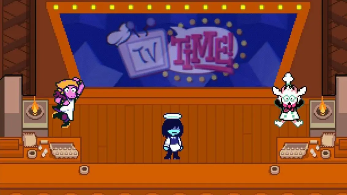Ein vergrößerter Screenshot aus Deltarune Kapitel 3, der Susie, Kris und Ralsei in der Kochshow zeigt.