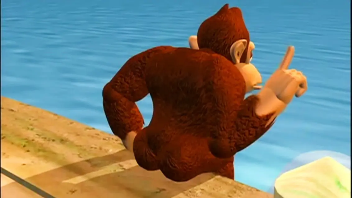 Donkey Kong sitzt auf einem Boardwalk und hebt einen Finger mit dem Rücken zur Kamera.